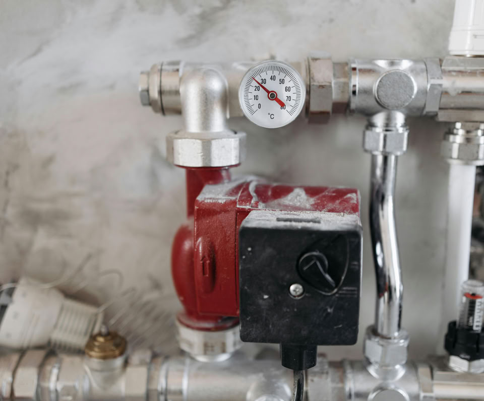 Close-up view of an industrial plumbing system featuring a pressure gauge and steel pipes.