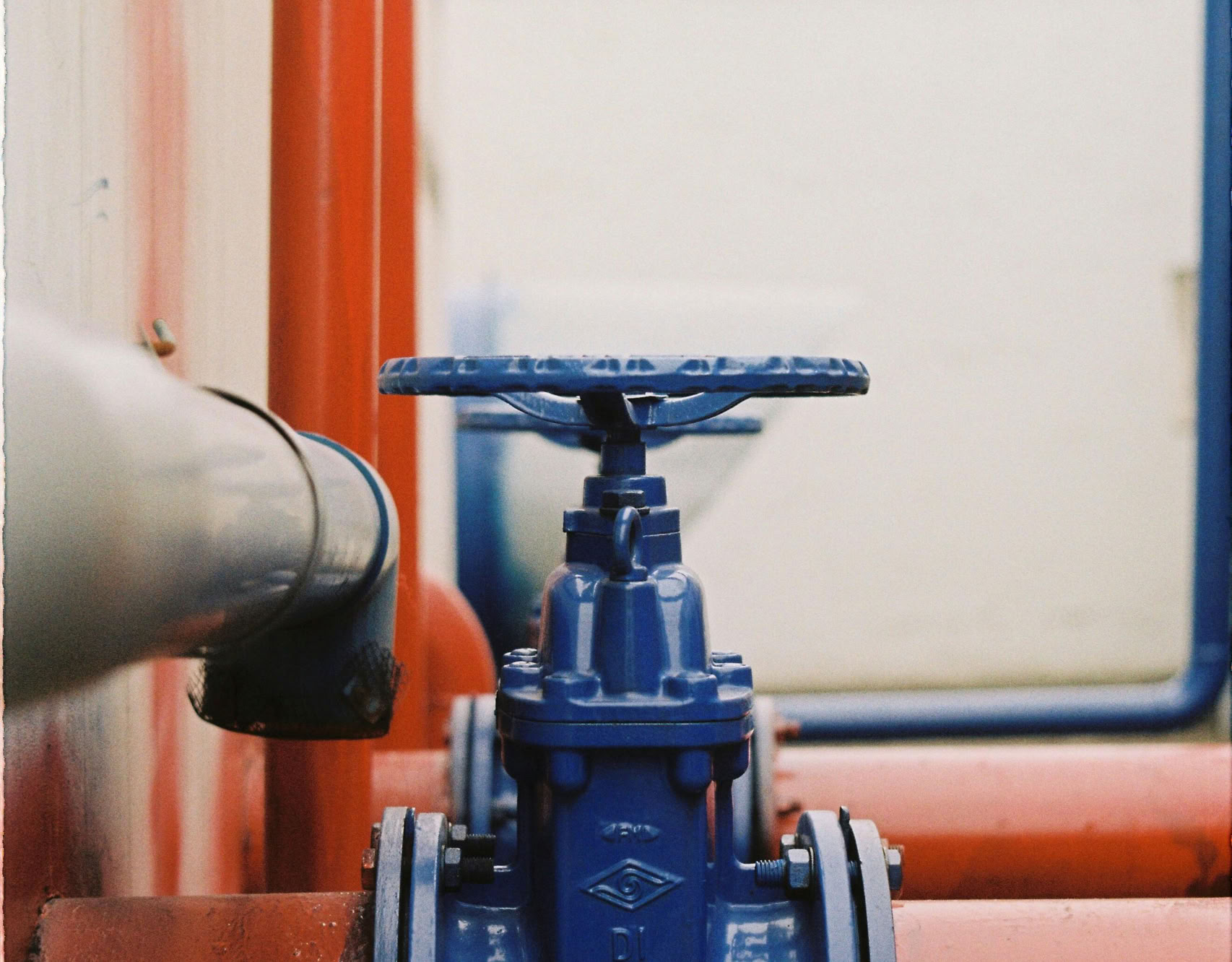Close-up of a blue gate valve on red pipes, showcasing industrial plumbing.